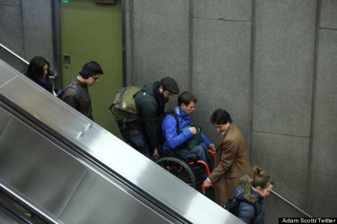 Justin Trudeau helping to carry someone in a wheelchair down an escalator