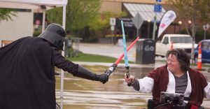 Michelle in wheelchair with lightsaber fighting Dart Vader