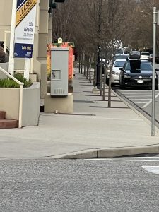 A sidewalk full of trees and electrical boxes
